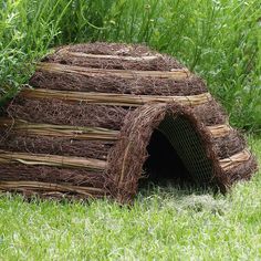 a dog house made out of hay in the grass