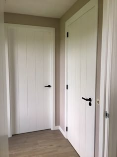 an empty room with two white doors and wood flooring on either side of the door