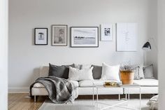 a living room filled with white furniture and pictures on the wall above it's couch