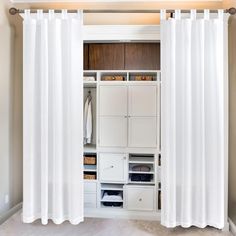 an open closet with white curtains hanging from the ceiling