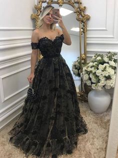 a woman taking a selfie in front of a mirror wearing an off the shoulder black dress