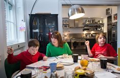 three people sitting at a table with food in front of them and one person pointing