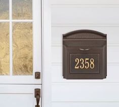 a mailbox on the side of a white house with gold foiled window and door