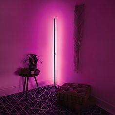 a room with purple lighting and a small table in front of the wall, next to a plant