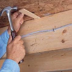 a man holding a hammer and working on the ceiling in a house that is under construction