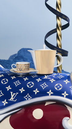 a coffee cup and saucer on top of a table with a blue sky in the background