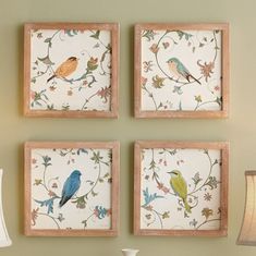 three birds are hanging on the wall next to a lamp and table with two vases