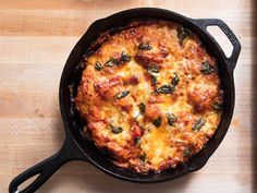 a casserole dish with cheese and spinach in a cast iron skillet