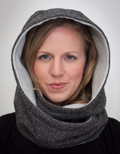 a woman wearing a gray and white hoodie with her face covered by a scarf