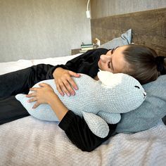 a woman laying on top of a bed holding a stuffed animal