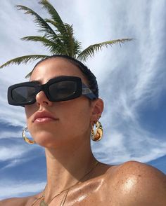 a woman wearing sunglasses and a palm tree in the background