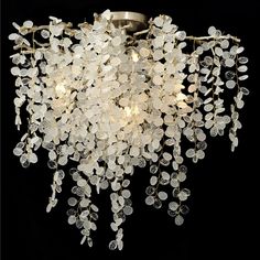 a chandelier with white flowers hanging from it's ceiling and black background