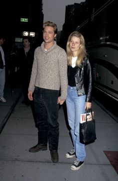 a man and woman holding hands on the sidewalk