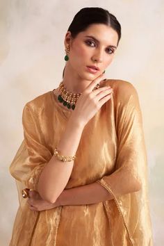 Gold tissue kaftan style kurta with lace trims and tassel hem. Comes with soft modal gold pant.
Component: 2
Pattern: Solid
Neckline: V-Neck
Sleeve Type: Batwing
Fabric: Kurta: Tissue, Pant: Soft Modal
Color: Gold
Other Details: 
Tassel hem
Lace trims
Side slits
Note: Inner worn by the model is not for sale
Occasion: Mehendi and Haldi - Aza Fashions Festive Kurta With Back Tassel Tie-up For Eid, Bollywood Style Festive Kurta With Back Tassel Tie-up, Festive Bollywood Kurta With Back Tassel Tie-up, Festive Kurta With Back Tassel Tie-up For Diwali, Elegant Eid Sets With Tassels, Elegant Saree Set With Tassels, Elegant Sets With Tassels For Diwali, Eid Sharara With Latkans, Kaftan Kurta