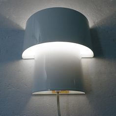 a wall light with a white shade on it's side and a yellow cord attached to the lamp