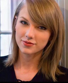 a close up of a person wearing a black shirt and blonde hair with blue eyes