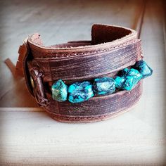 Distressed Finish Leather Cuff features a genuine strand of chunky African Turquoise. Each strand is different and will show varying shades of the natural stone. ***Please view all the pictures as they show examples of the many stone colors Cuff measures 2" by 9" in length Adjustable to 7" and 7.5" Although your item will resemble the photo, each piece is created by hand, so no two are identical.Thank you for visiting The Jewelry Junkie! Adjustable Turquoise Cuff Bracelet With Natural Stones, Southwestern Adjustable Cuff Bracelet With Natural Stones, Adjustable Turquoise Bracelets With Patina, Adjustable Turquoise Bracelet With Patina, Adjustable Turquoise Leather Bracelet In Rustic Style, Adjustable Rustic Turquoise Leather Bracelet, Rustic Turquoise Jewelry For The Beach, Rustic Handmade Turquoise Cuff Bracelet, Bohemian Turquoise Cuff Bracelet With Patina