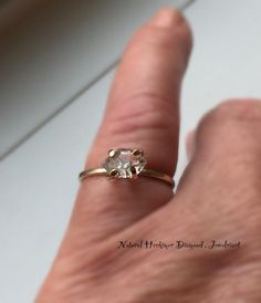 a person's hand with a ring on it that has a diamond in the middle