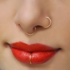 a woman with red lipstick and gold nose ring