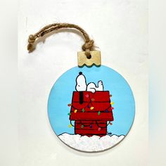 a wooden ornament with a snoopy christmas decoration hanging from a rope on a wall