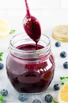 a jar filled with blueberry jam next to sliced lemons