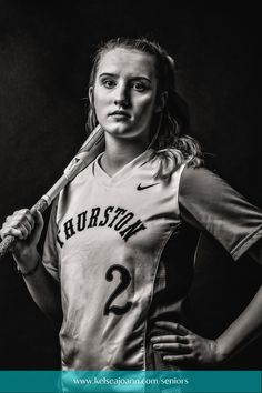 a woman holding a baseball bat and posing for a black and white photo with her hands on her hips