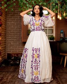 This stunning Habesha Kemis is a true work of art, featuring a mesmerizing Tilf pattern and the traditional elegance of the Shimena style. The intricate Tilf embroidery is expertly crafted, showcasing the beauty and richness of Ethiopian design. The flowing skirt and elegant neckline of the Kemis are designed to be both comfortable and flattering, making it the perfect choice for any special occasion. The vibrant colors of the Tilf pattern are both eye-catching and regal, adding to the overall b Festive Anarkali Dress With Woven Motifs, Traditional Ceremony Dresses With Woven Motifs, Bohemian Dress For Diwali Traditional Ceremonies, Traditional Embroidered Cutdana Wedding Dress, Traditional Wedding Embroidered Dress With Cutdana, Traditional Embroidered Wedding Dress With Cutdana, Festive White Dresses With Woven Motifs, Festive White Dress With Woven Motifs, Anarkali Dress With Woven Motifs For Traditional Ceremonies