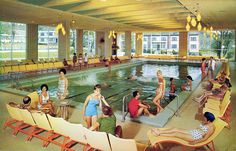 an indoor swimming pool with people sitting and standing around it