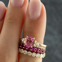 a woman's hand holding a pink and white diamond ring