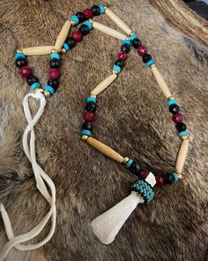 the necklace is made with beads and wooden sticks, which are attached to a cow's fur