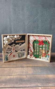 two small christmas cards are sitting on a wooden table, one is open and the other is closed