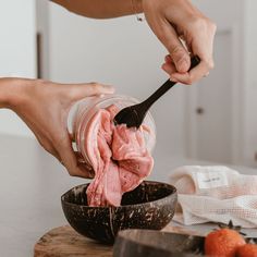 a person is scooping ice cream into a bowl with strawberries on the side