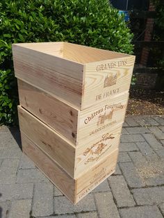 a large wooden box sitting on top of a brick sidewalk next to bushes and shrubbery