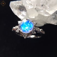 a blue ring sitting on top of a rock next to crystal stones and crystals in front of a black background