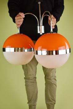 the person is holding two orange and white lamps in front of their body, both with one light on each side