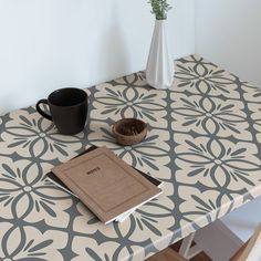 a table with a book, coffee cup and vase on it