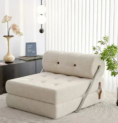 a white couch sitting on top of a rug next to a table with a plant