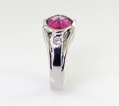 A dazzling pink Tourmaline checkerboard cut from Brazil is is accented with two flush set diamonds in this gorgeous 14k white gold ring. The natural Tourmaline is a 9 x 7 mm oval shape checkerboard cut and weighs 1.93 carats. The two diamonds are round brilliant cuts measuring 2.8mm with a total weight of .16 carats G-H color VS1-2 clarity The ring is 10.5 mm wide (3/8 inch) at the stone tapering down to 3.5 mm The height of the ring is 6 mm Ring weighs 7.31 grams Size 6 3/4 All items from Stowe Pink Fine Jewelry Birthstone Ring For Formal Occasions, Pink Sapphire Ring In Platinum For Anniversary, Pink Sapphire Platinum Ring For Anniversary, Pink Birthstone Ring With Accent Stones For Formal Occasions, Pink Platinum Diamond Ring For Anniversary, Pink Birthstone Ring For Formal Occasions, Pink Sapphire Ring With Bezel Setting For Wedding, Formal 14k White Gold Pink Rings, Formal Pink Birthstone Ring With Center Stone