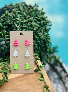 the earrings are made out of plastic and have trees on them, as well as green leaves