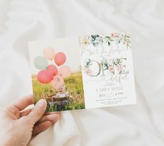 a person holding up a card with balloons on it and the word love is in the air