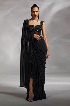 Black georgette pre-draped saree with ruffle details near the slit. Comes with padded corset blouse.
Component: 2
Pattern: Embroidery
Neckline: Sweetheart
Sleeve Type: Sleeveless
Fabric: Corset: Satin and Tulle, Saree: Georgette
Color: Black
Other Details: 
Attached lining
Weight approx (in kg) : 1.2
Note: The neckpiece worn by the model is not for sale
Occasion: Sangeet - Aza Fashions Corset Sari Blouses, Drape Saree Designer 2023, Black Corset Blouse, Sweetheart Neckline Blouse Pattern, Corset Saree Blouse Design, Corset Outfit Indian, Pre Draped Saree Gown, Saree With Corset Blouse, Indian Corset Blouse