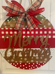 a christmas ornament hanging on the front door with red and green plaid ribbon