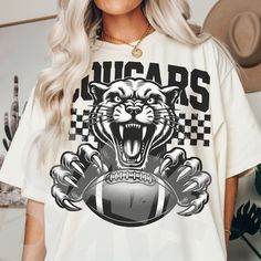 a woman wearing a t - shirt with an image of a tiger holding a football