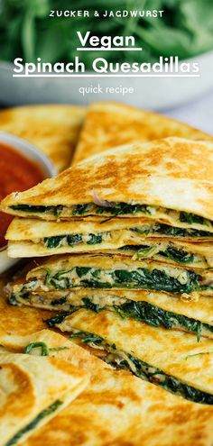 spinach quesadillas stacked on top of each other with salsa in the background