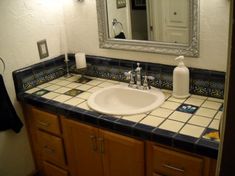 a bathroom sink sitting under a mirror next to a counter top with soap dispenser