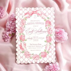 a pink and white bridal shower card with flowers on it, surrounded by pink satin