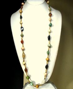 a white mannequin holding a multi colored beaded necklace