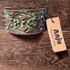 a metal bowl sitting on top of a wooden table next to a tag that says awn