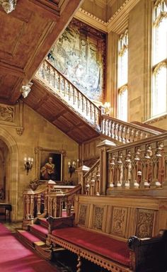 an ornate staircase with red carpet and wooden railings