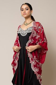 Burgundy georgette gathered kite style cape with mirror, swarovski, metallic sequins, studs and pearls hand embroidery. Comes with a black satin strappy jumpsuit. - Aza Fashions Red Sets With Mirror Work For Evening, Red Evening Sets With Mirror Work, Festive Mirror Work Kaftan With Cape Sleeves, Red Party Sets With Cape Sleeves, Festive Kaftan With Dupatta Cape, Elegant Embroidered Cape Dupatta, Festive Sheer Dupatta Kaftan With Cape Sleeves, Festive Embroidered Cape Kaftan, Red Cape